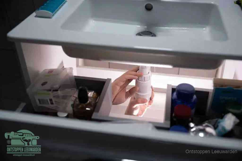 Een pompfles met zeep boven een wastafel, de heet water en afwasmiddel-methode om een vetprop in de afvoer los te maken in Leeuwarden