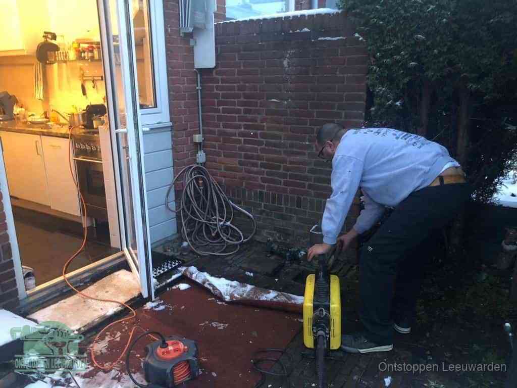 Een monteur werkt buiten bij een open riool-/grondput met een elektrische ontstoppingsmachine om een verborgen afvoerprobleem op te sporen in Leeuwarden