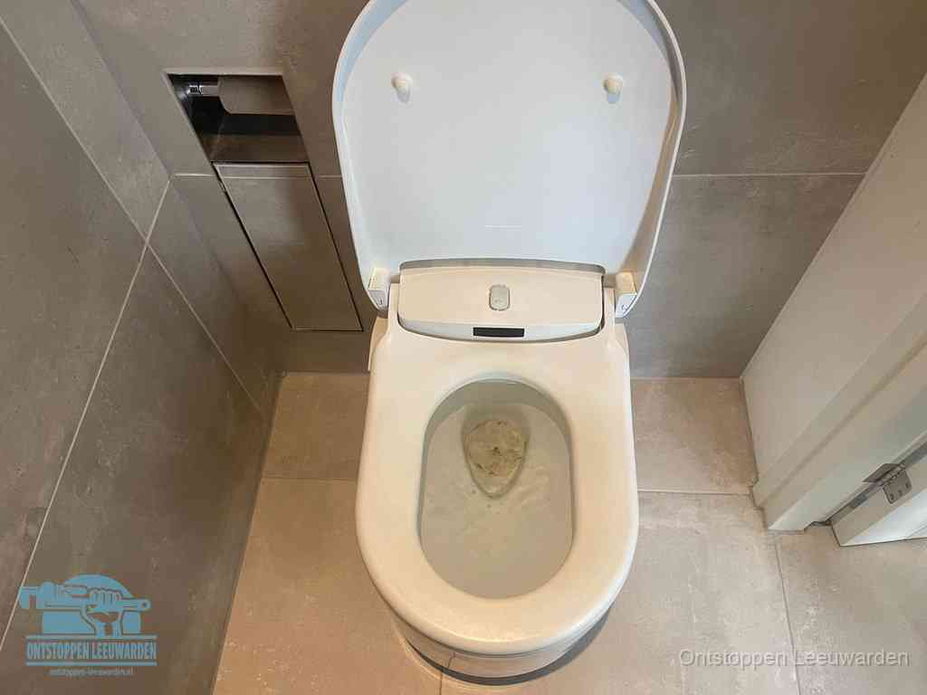 Een wit hangtoilet waarin een prop wc-papier op het water blijft drijven, een duidelijk signaal van een verstopte wc in Leeuwarden