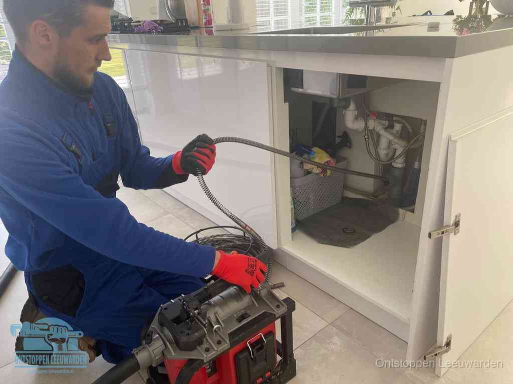 Een monteur reinigt de keukenafvoer grondig met een veermachine om terugkerende gootsteenverstoppingen te voorkomen in Leeuwarden