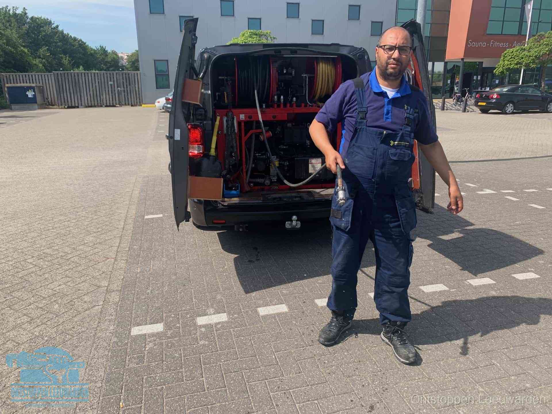 Een monteur bij zijn bestelbus met een hogedruk- en rioolreinigingsunit, klaar om de oorzaak van terugkerende wc-verstoppingen aan te pakken in Leeuwarden