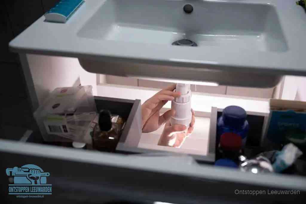 Een pompfles met zeep boven een wastafel in de toiletruimte, de warm water en afwasmiddel-methode om de wc te ontstoppen in Leeuwarden