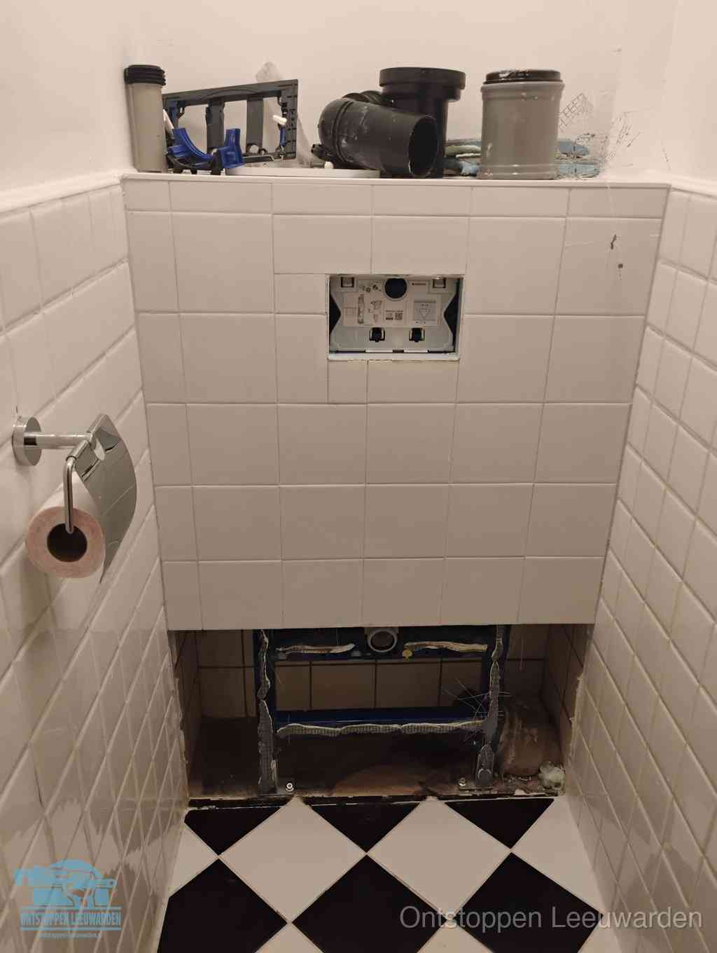 Een toiletruimte waar het hangtoilet en de inbouwreservoir-onderdelen zijn vrijgelegd voor onderhoud, periodiek nazicht voorkomt een wc-verstopping in Leeuwarden