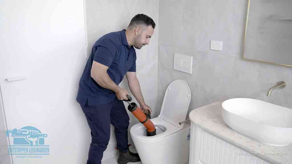 Een monteur gebruikt een handmatige perspomp (toiletontstopper) op een wandcloset tijdens het professioneel wc ontstoppen in Leeuwarden